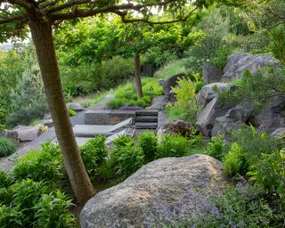 sloped garden with natural rock boulders and terraces, loungers and view
