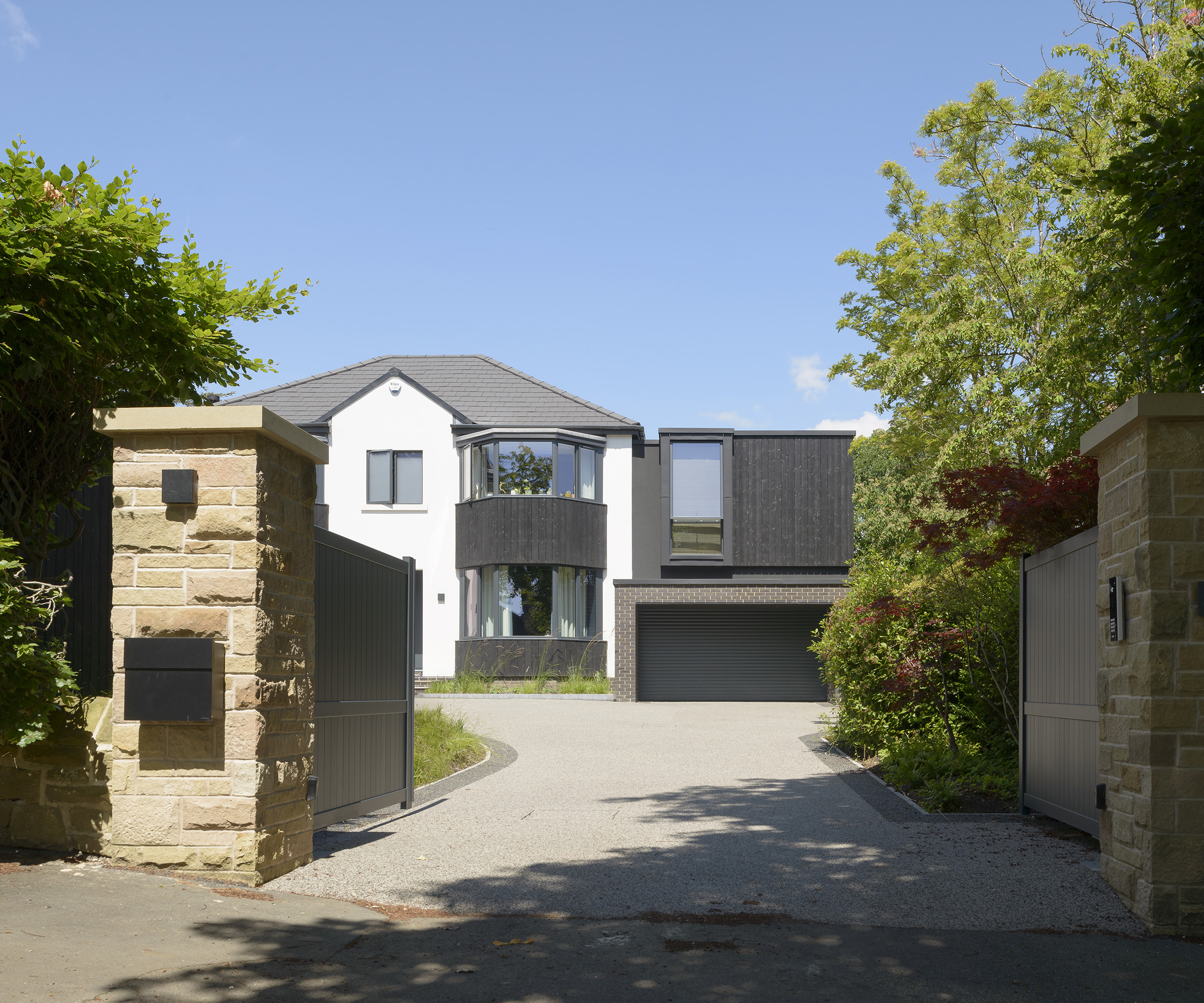 Exterior of a 1930s detached home with a gated front leading to a driveway