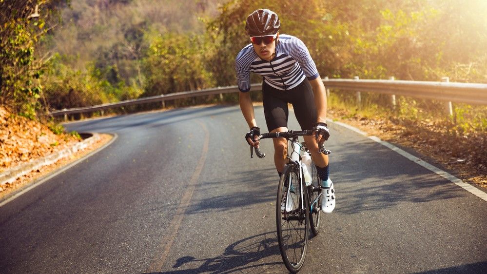 a photo of a man cycling on a road bike 