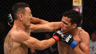 UFC fighters Charles Oliveira and Max Holloway throwing punches at each other