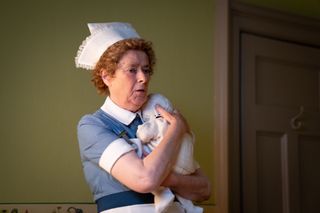 Linda Basset as Nurse Phyllis Crane holding a baby
