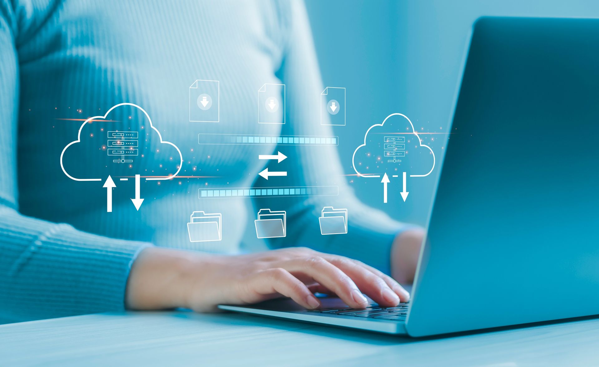 A representation of cloud backup and cloud storage overlayed on a person using a laptop.