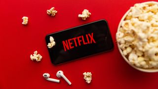Netflix logo op een smartphone naast een bak popcorn
