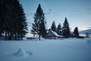 View of the Glass Cabin, Czech Republic, by Mjölk Architects, in the snow at dusk