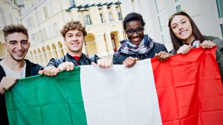 Mixed race young friends holding Italian flag - stock photo