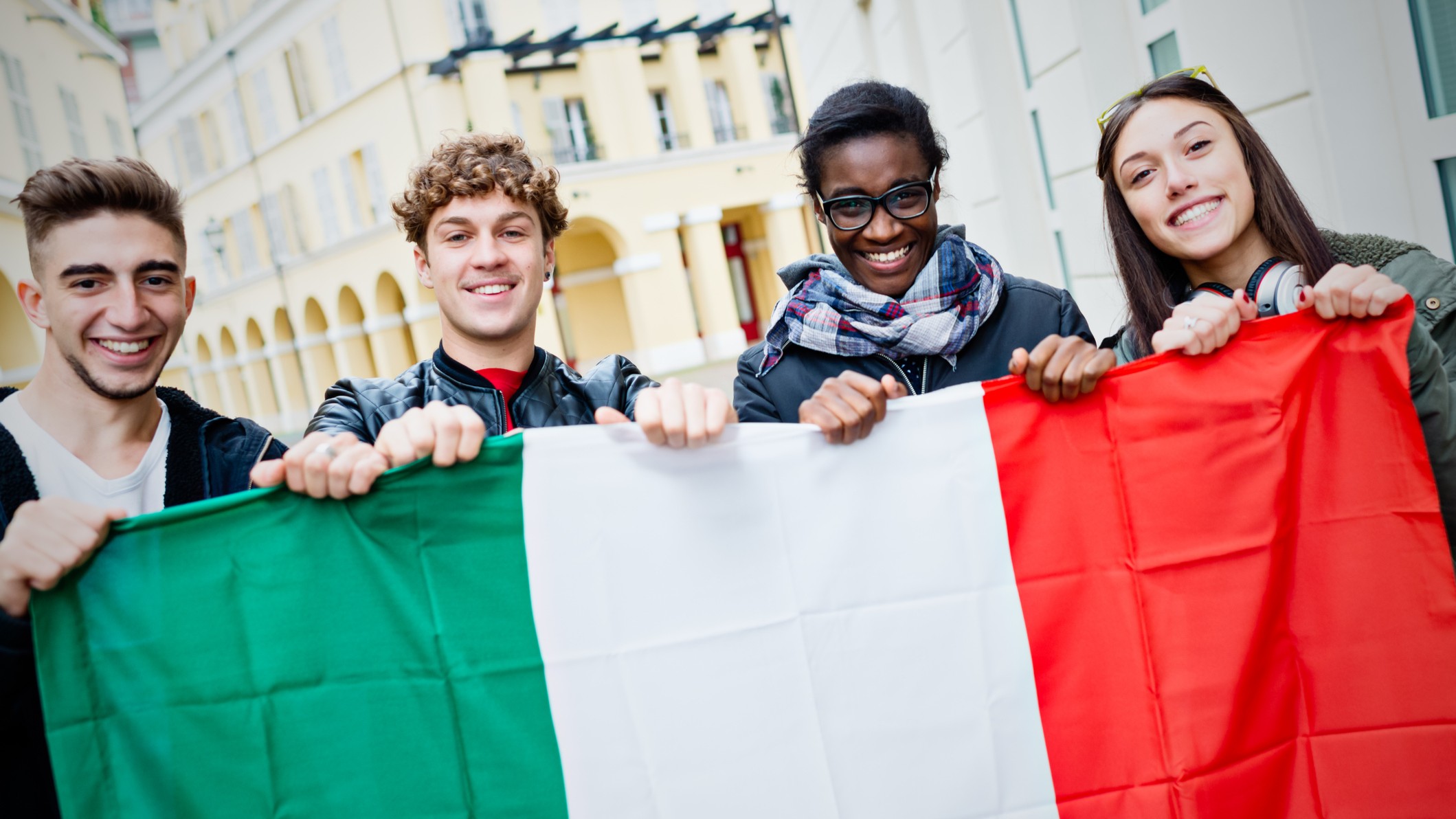 Mixed race young friends holding Italian flag - stock photo