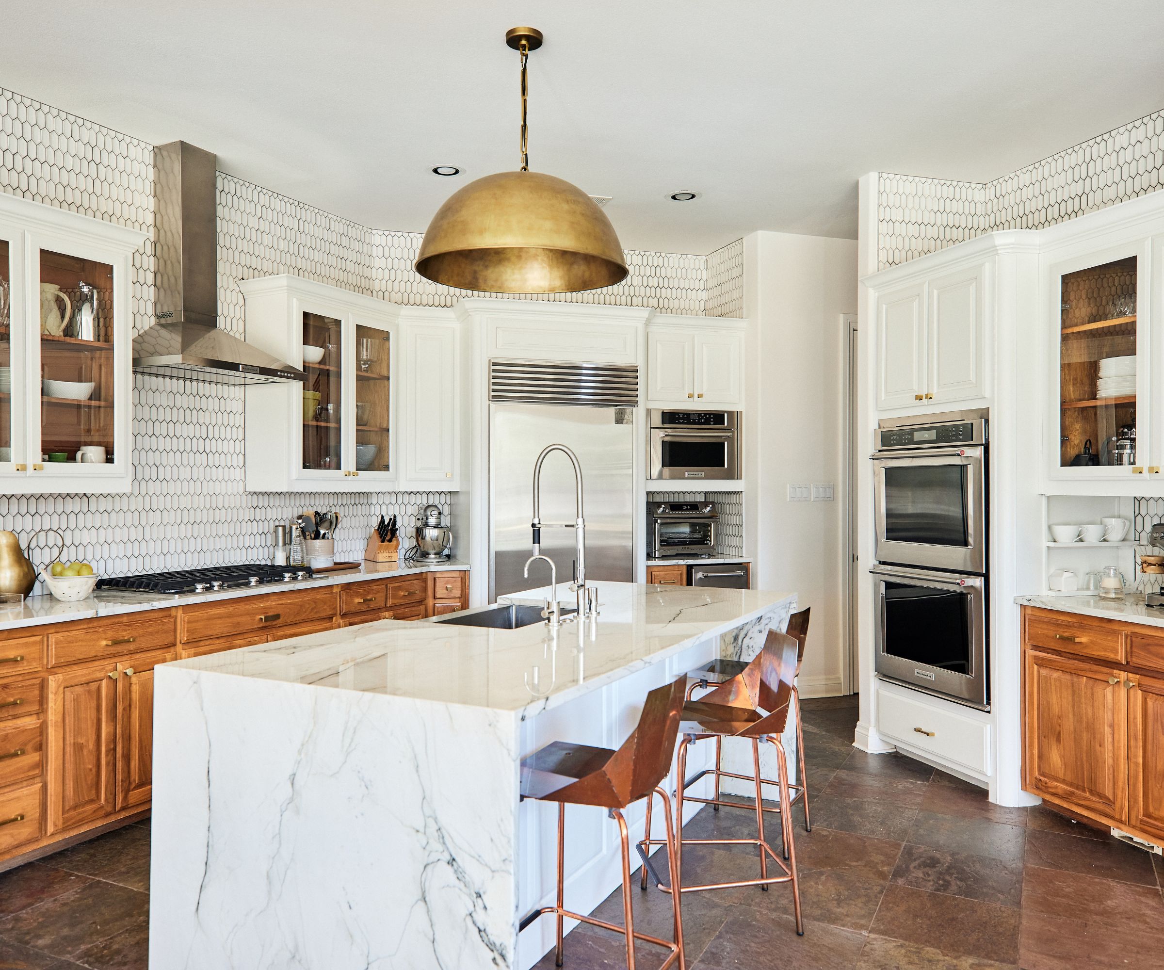 kitchen with white walls and mix of wooden and white cabinets and island with counter stools large pendant above
