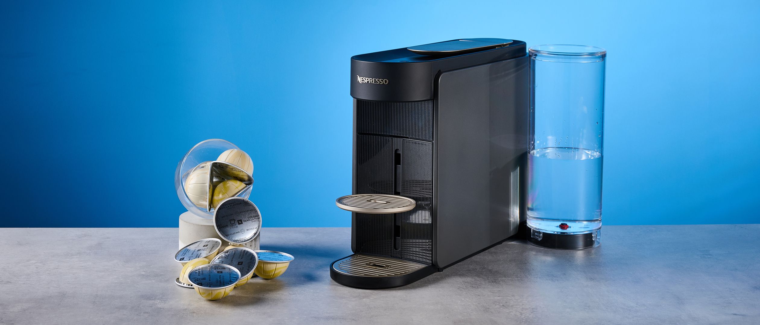 the nespresso vertuo up machine photographed against a blue background