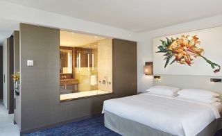 Bedroom featuring a large piece of artwork, and a window into the en-suite bathroom