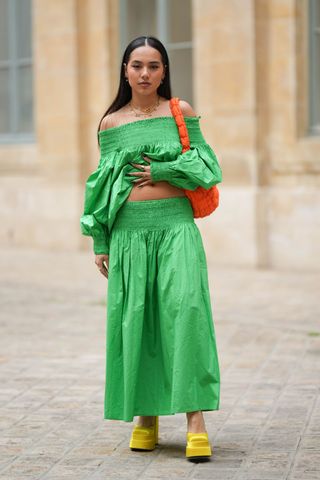 A guest wearing green outside the COS show 2023
