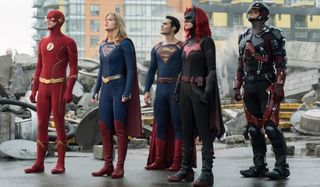 Supergirl stands with her fellow heroes amid some rubble