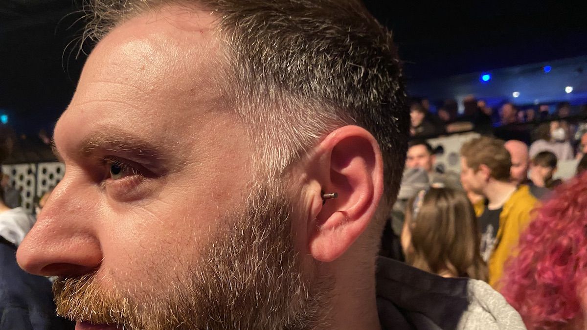 Man at a live musi venue surrounded by people with earplugs in his ears