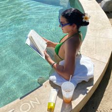 @ladhav wearing a green bikini and reading a book in the pool