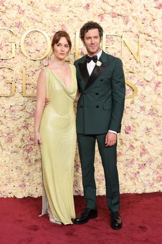 Leighton Meester wearing a lime green gown and Adam Brody wearing a green tux posing on Golden Globes 2025 red carpet