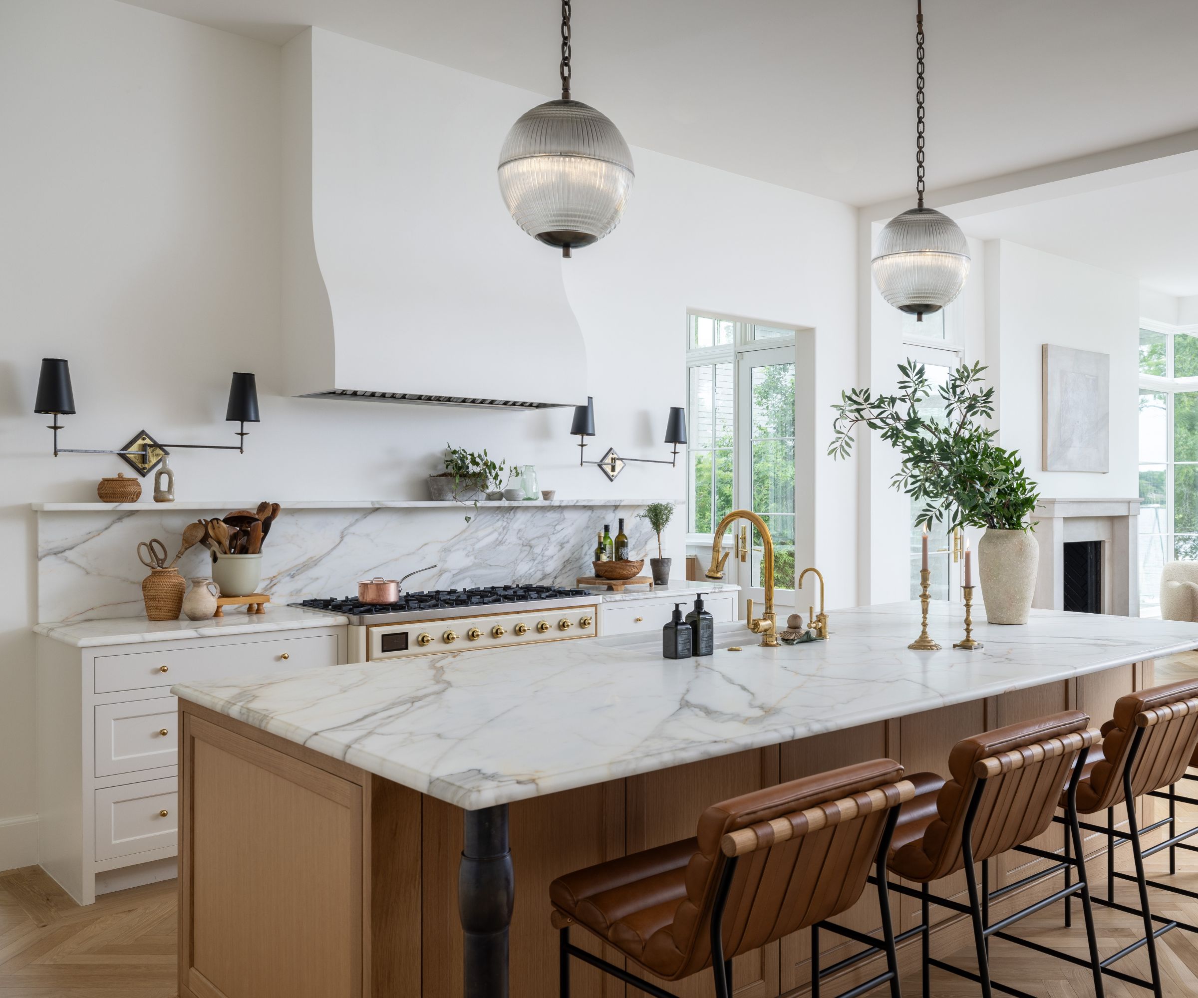 A neutral kitchen with white cabinets, a wooden island, and marble countertops