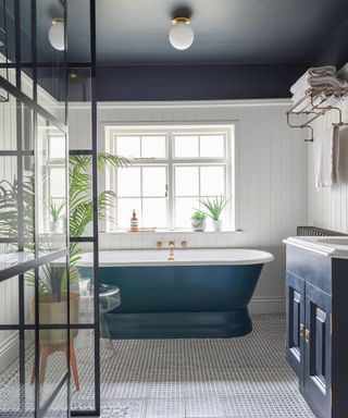 An example of white bathroom ideas showing a white bathroom with a blue ceiling, a blue bath and a vanity