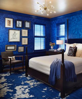 how to make a bedroom darker, bedroom with blue wallpaper, blue rug, mahogany bed, blue blinds, artwork