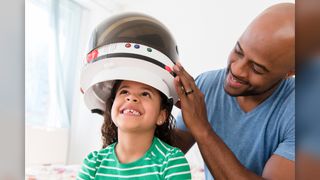 A girl tries on a astronaut helmet with her dad