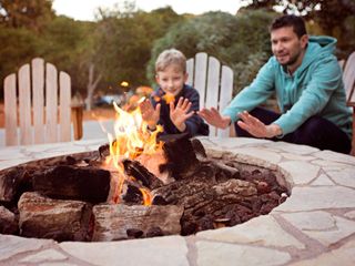 A father and son warm their hands over a fire pit