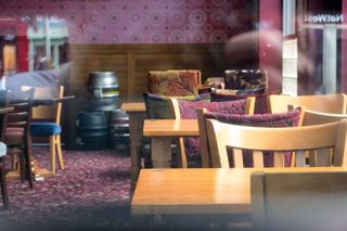 a medium shot showing the inside of a closed Wetherspoons pub with empty tables and chairs