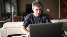 An older man works on his laptop in his living room.