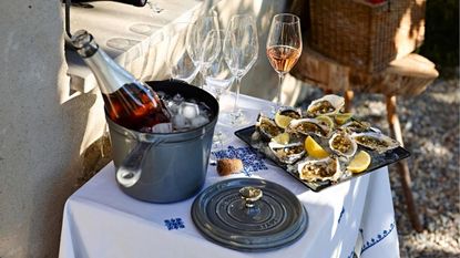 A ros&eacute; bottle in a grey Staub Cast-Iron Fonte Sauce Pot, next to a platter of oysters