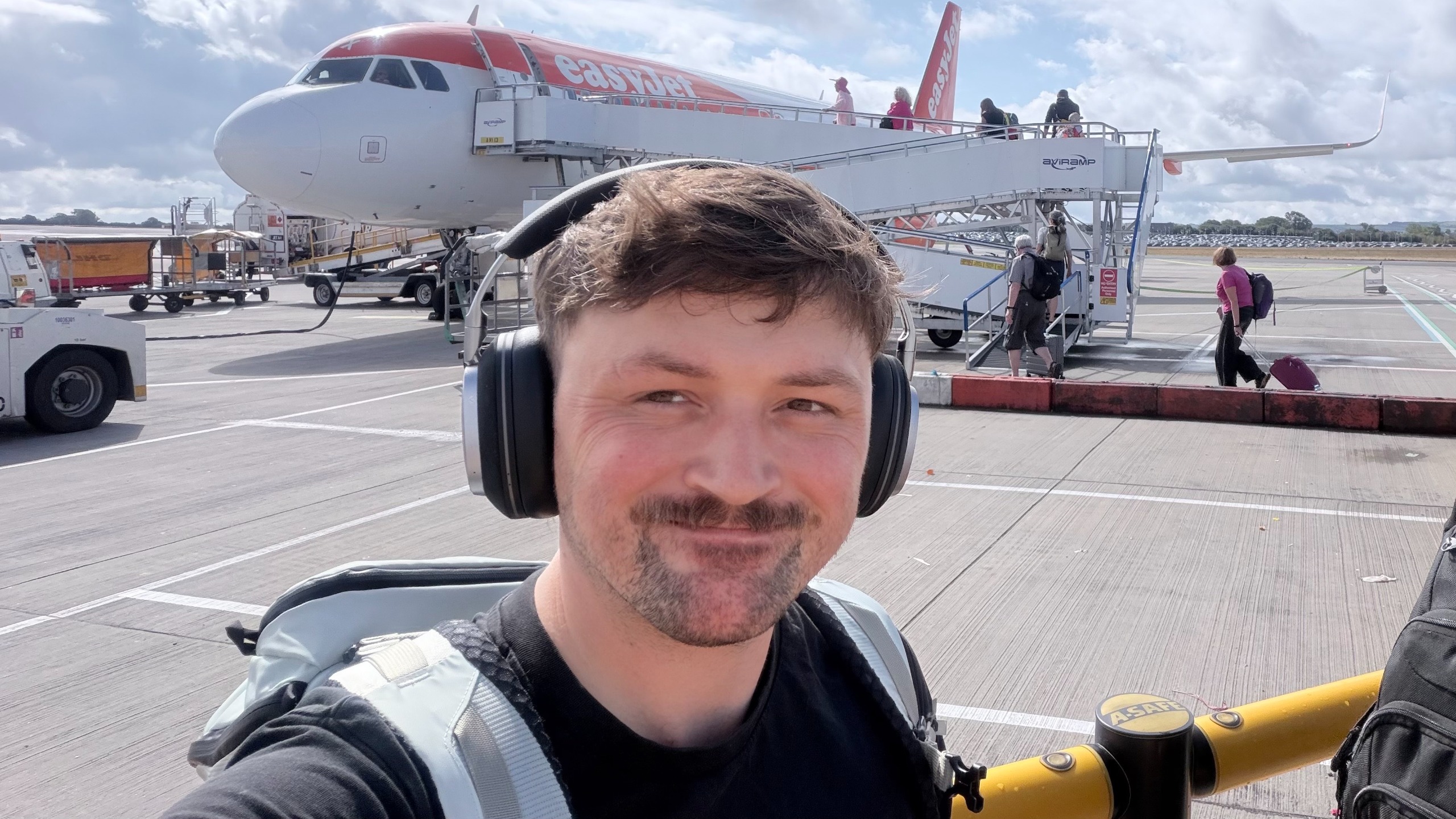 A selfie photo of Editor Peter Wolinski wearing a set of the Noble Audio FoKus Artemis on a runway as he is about to board a plane.
