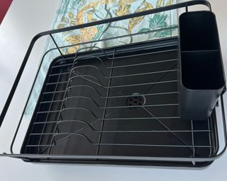 A black dish drying rack on a blue patterned table runner and white table