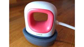 Best Cricut machines; a small red and white iron-shaped gadget, the Cricut EasyPress Mini shows a photo of the device in raspberry