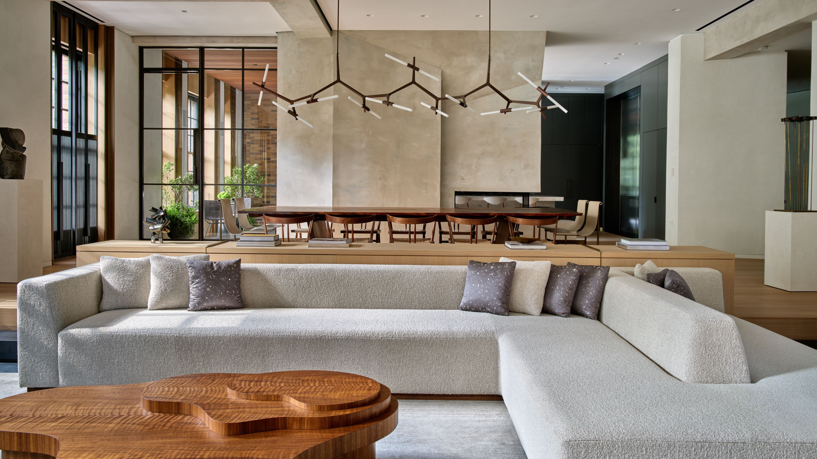 Modern open plan living room with large gray sofa, wooden coffee table and view of a large dining table beyond