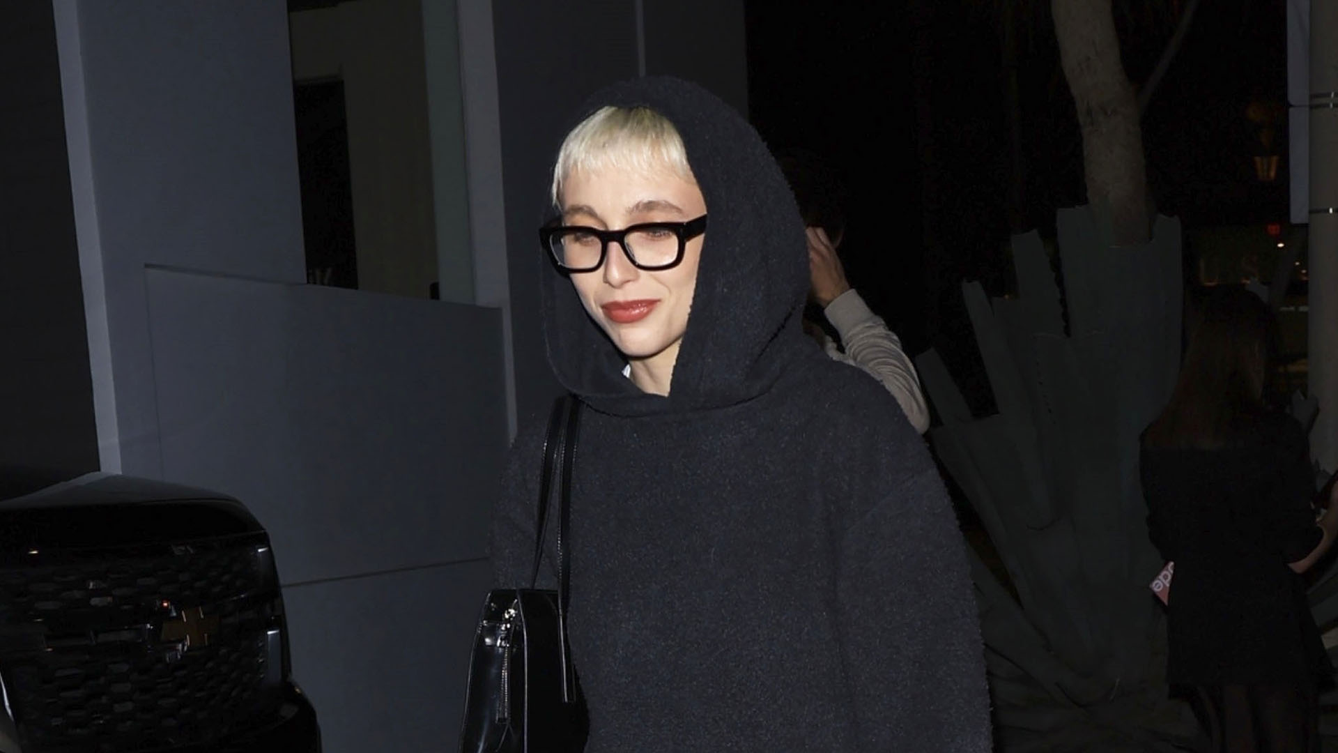 Emma Chamberlain wearing a gray knit set and slouchy black boots