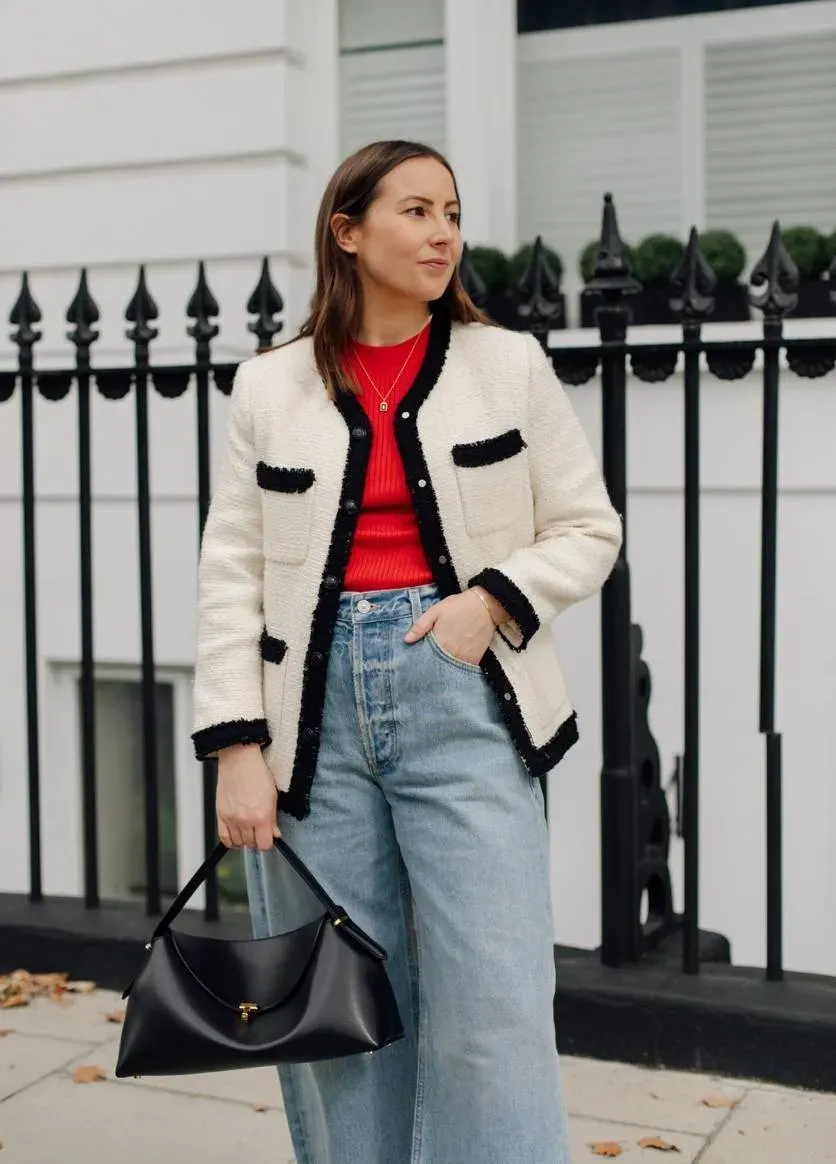 Emily Dawes, senior shopping editor, wears boucle jacket, red top, blue jeans and black toteme handbag on the street.