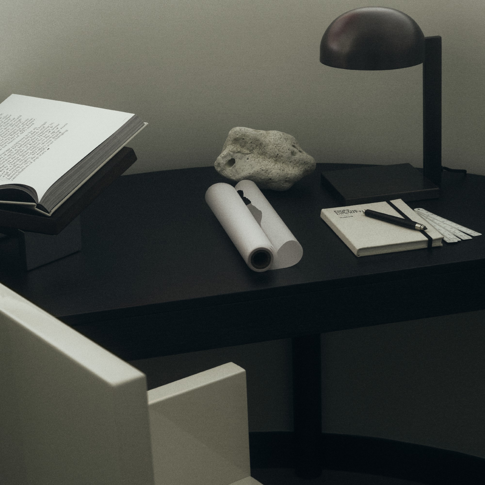 A black desk with a metal table lamp and a wooden book stand on top
