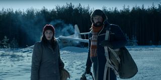 Joyce (Winona Ryder) and Murray (Brett Gelman) outside of a crashed plane in a snowy scene in an official image from Stranger Things season 4