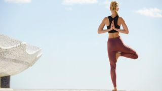 Woman practicing tree pose yoga on terrace