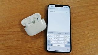 A pair of AirPods next to an iPhone with the AirPods name change screen showing