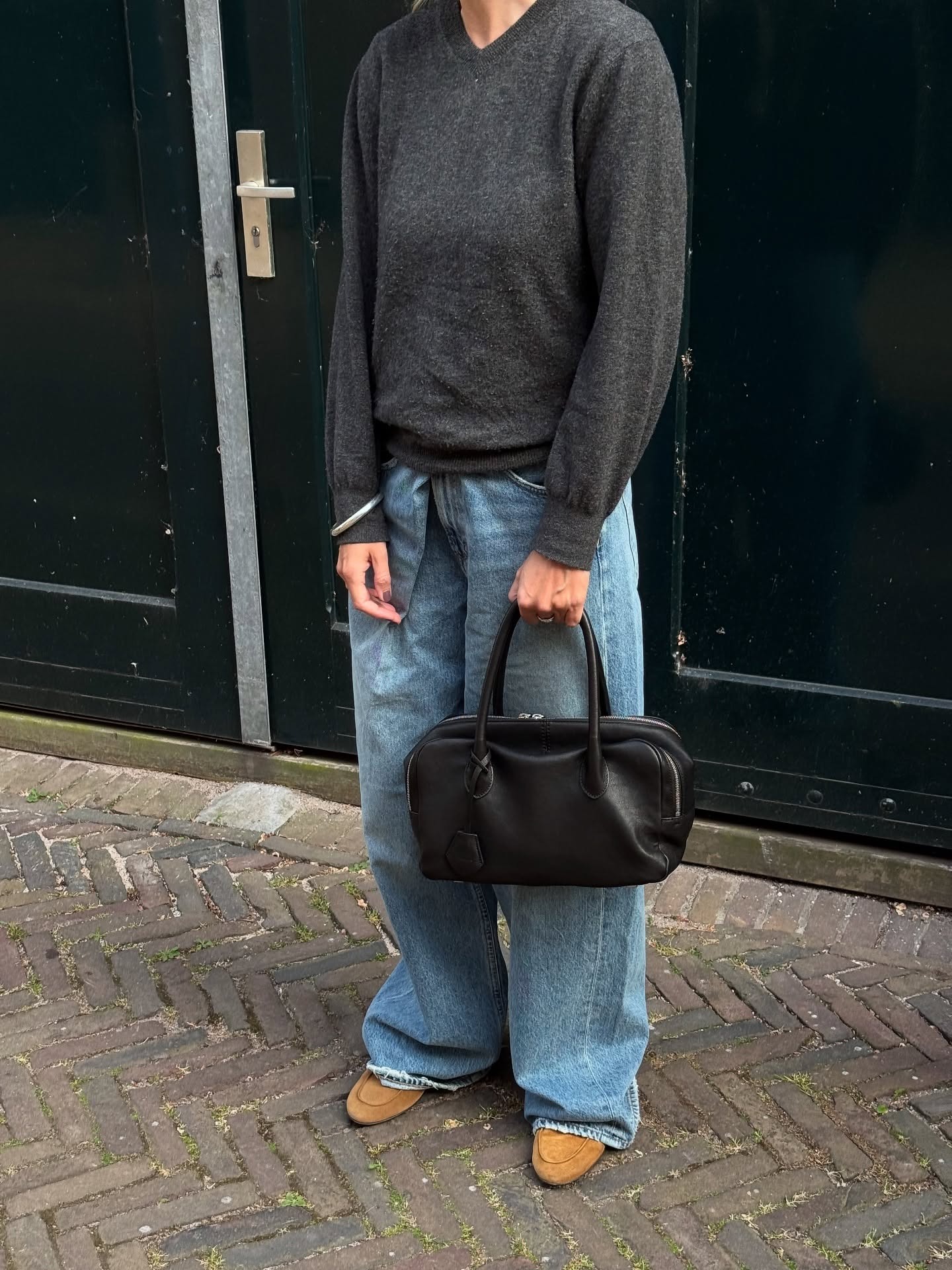 Influential @lindatol_Wears soft jeans with grey pullover and black leather east-west bag.