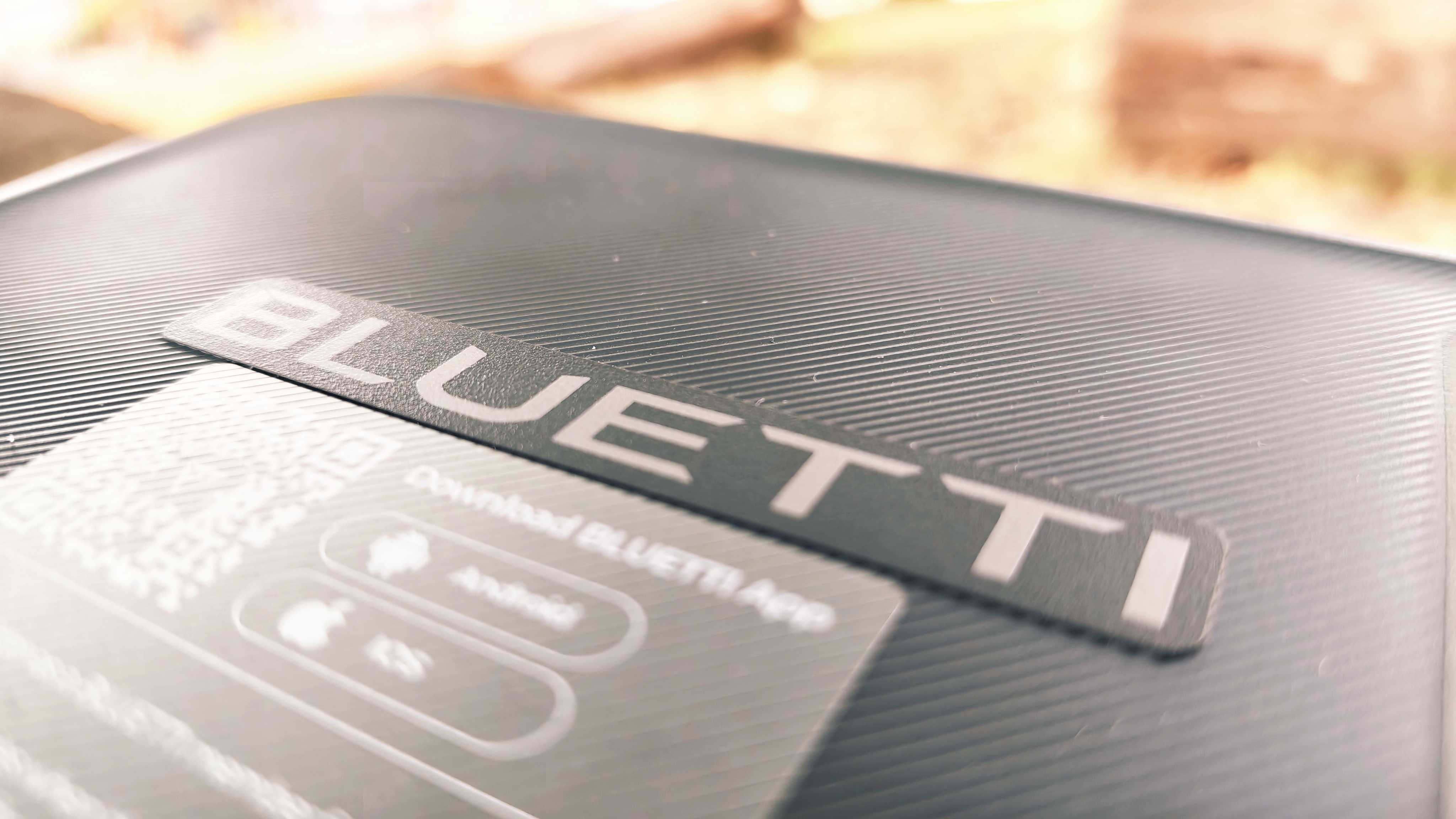 A grey Bluetti Elite 10 power station sitting on a log in a forest grove