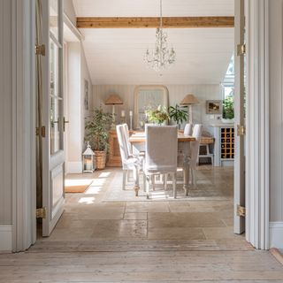 view through from hallway with wooden flooring to dining room with stone floor and neutral furnishings