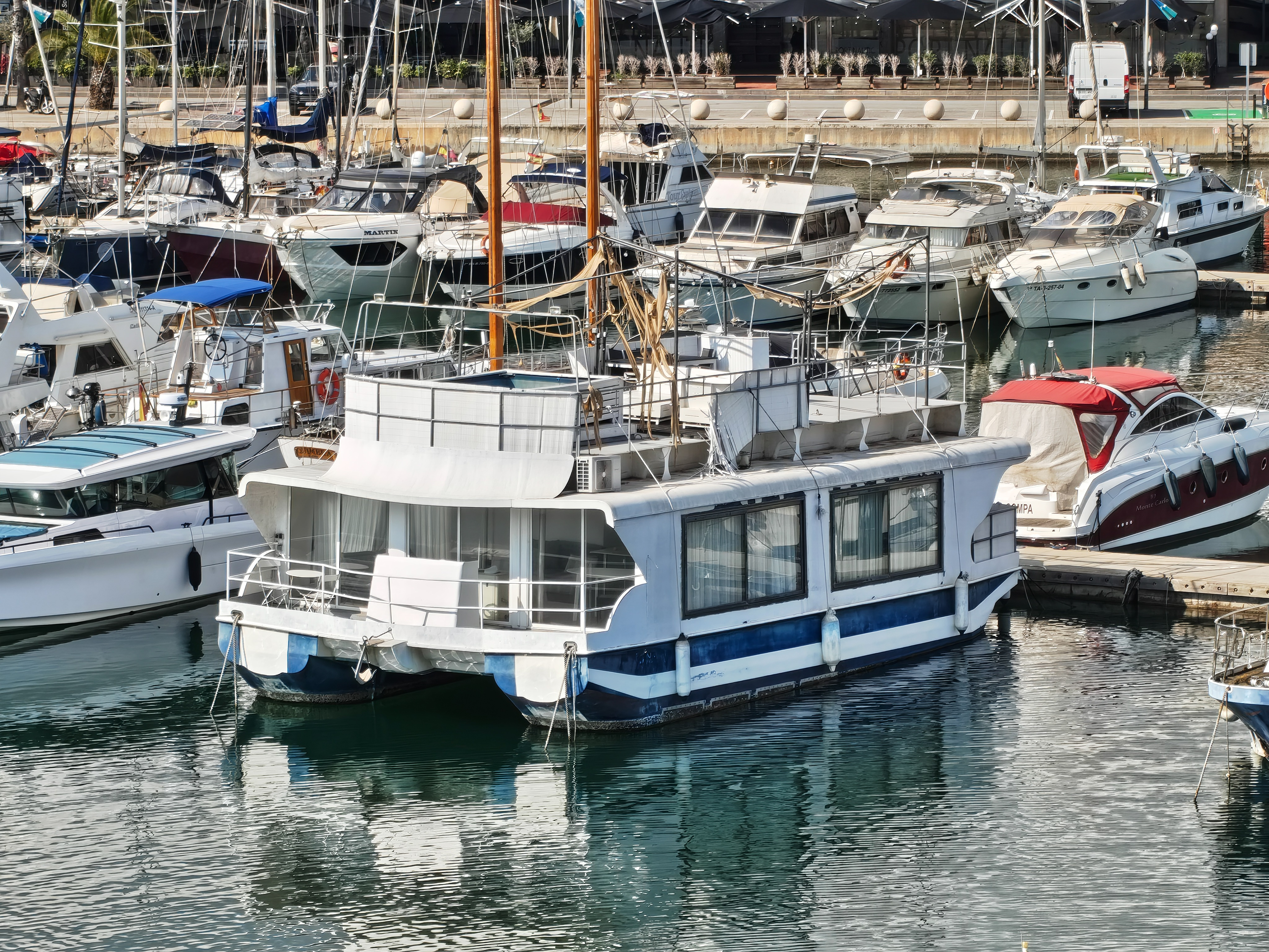 Close-up of a houseboat-style vessel moored among other boats in a Barcelona marina, photographed with the Nothing Phone (4a).