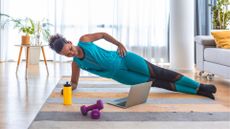 woman in side plank on a yoga mat at home