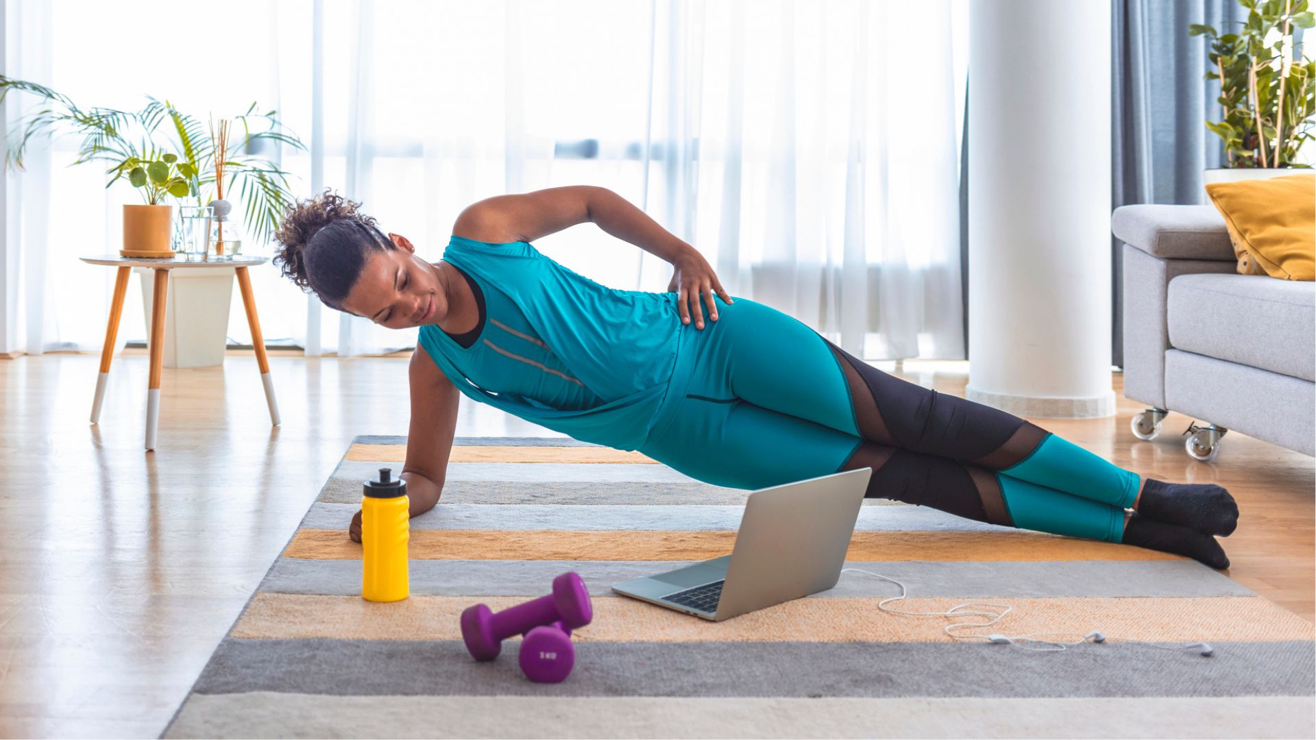 woman in side plank on a yoga mat at home