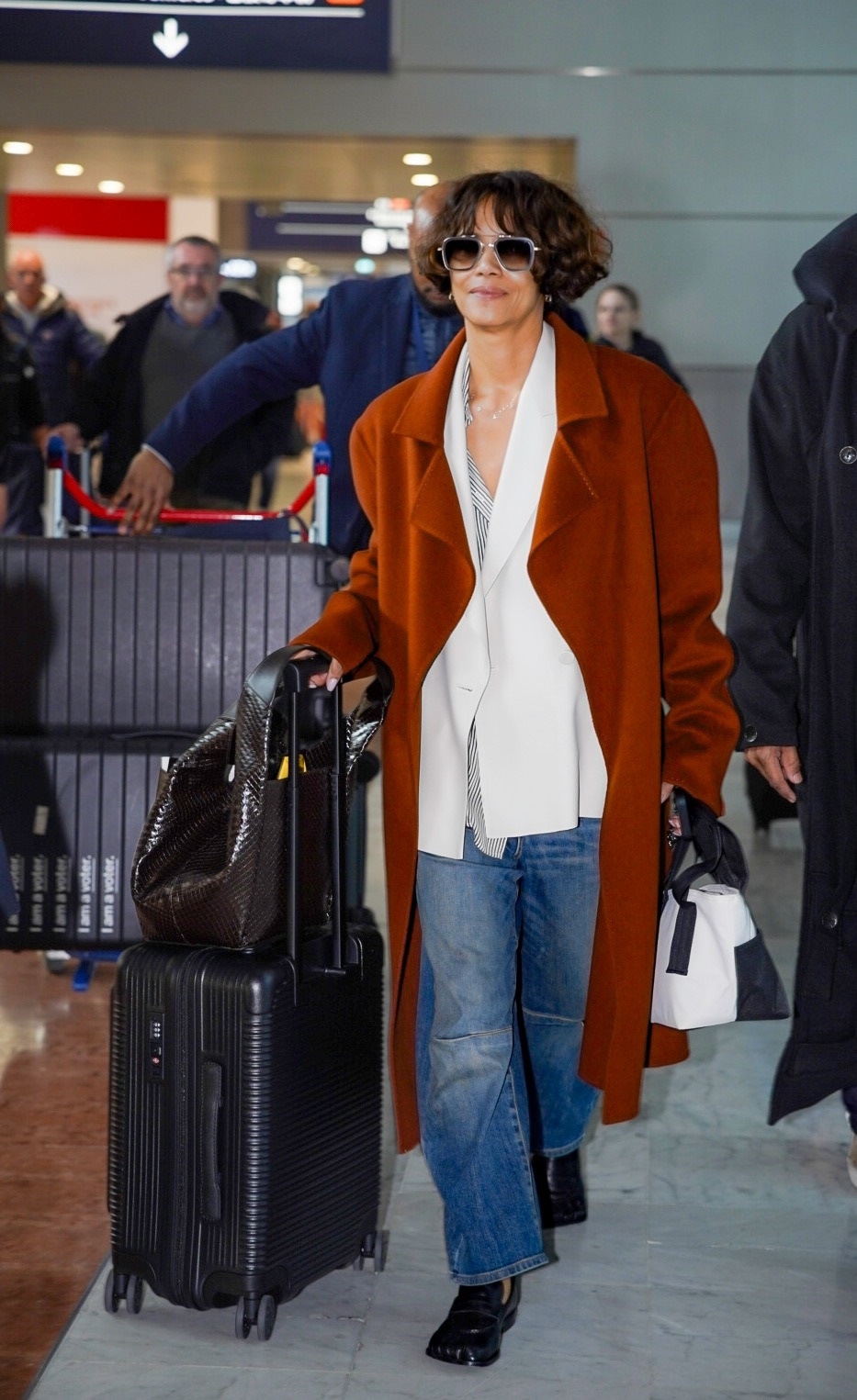 Halle Berry leaves the airport wearing jeans with loafers and a red jacket.