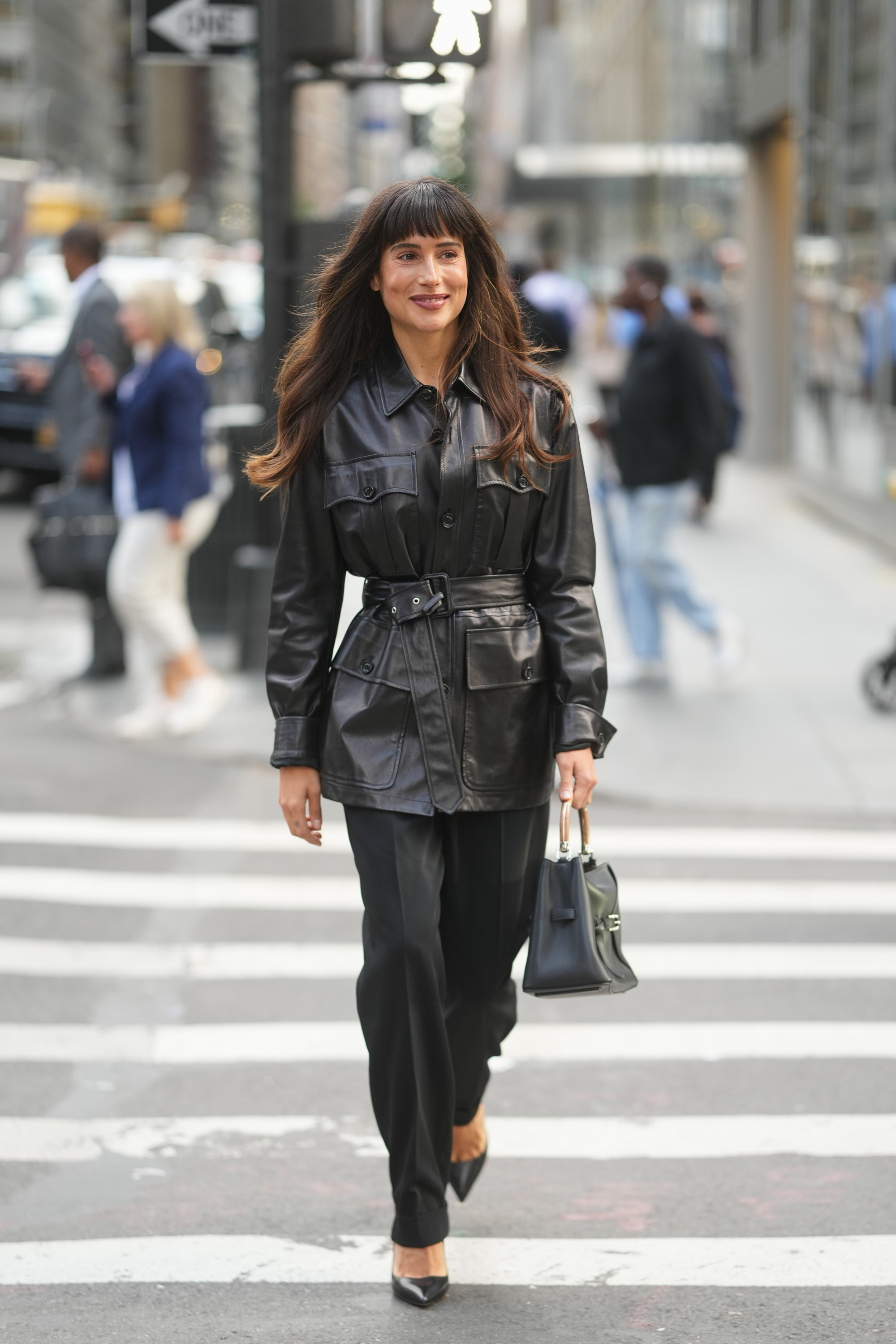 a woman wearing a black leather jacket, black pants, and black heels with blunt bangs during new york fashion week