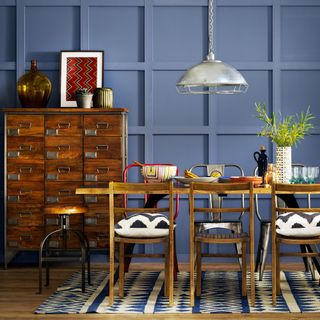 Blue dining room with wall panelling, wooden furniture and patterned rug