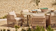 Woven wicker patio chairs around an outdoor table, on a brick patio.