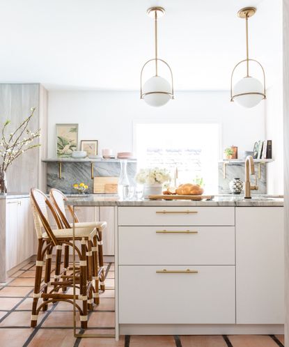 A small neutral kitchen with wooden flooring, white cabinets, and a gray marble countertop