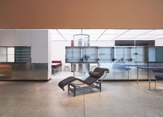 A model of a reclining lounge chair is shown in front of metal cabinets.