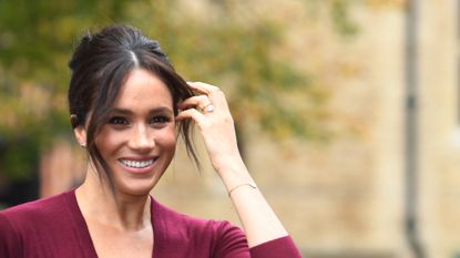 Meghan Markle smiling moving hair away from her face - meghan markle beauty line