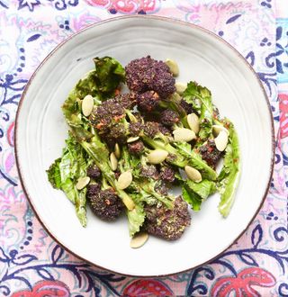 purple sprouting broccoli in a white bowl on a patterned tablecloth